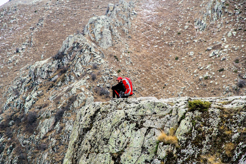 person in red jacket climbing on rocky mountain during daytime