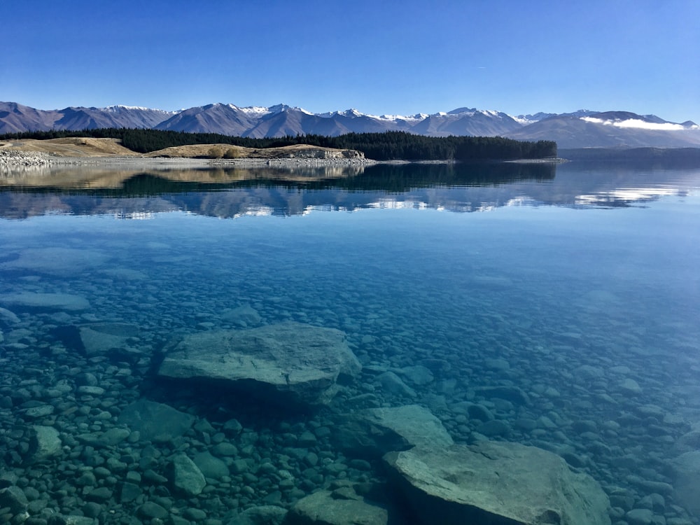 brown and white mountains beside body of water during daytime