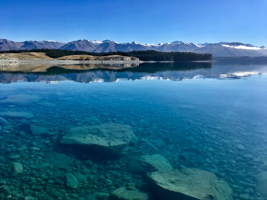 brown and white mountains beside body of water during daytime in Lake Pukaki New Zealand