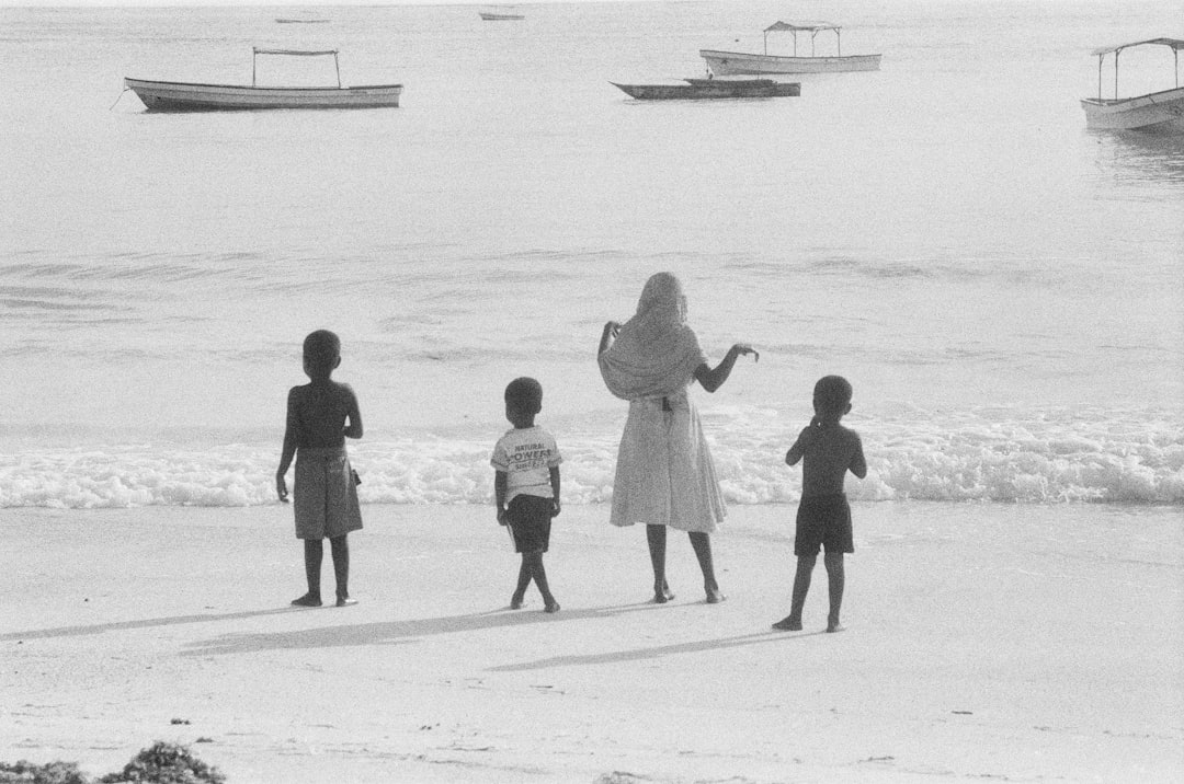 grayscale photo of 2 children and a girl walking on a beach