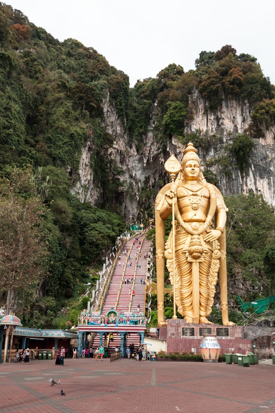 gold statue of man near body of water during daytime in Batu Caves Malaysia