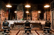 black leather barber chair near brown brick wall