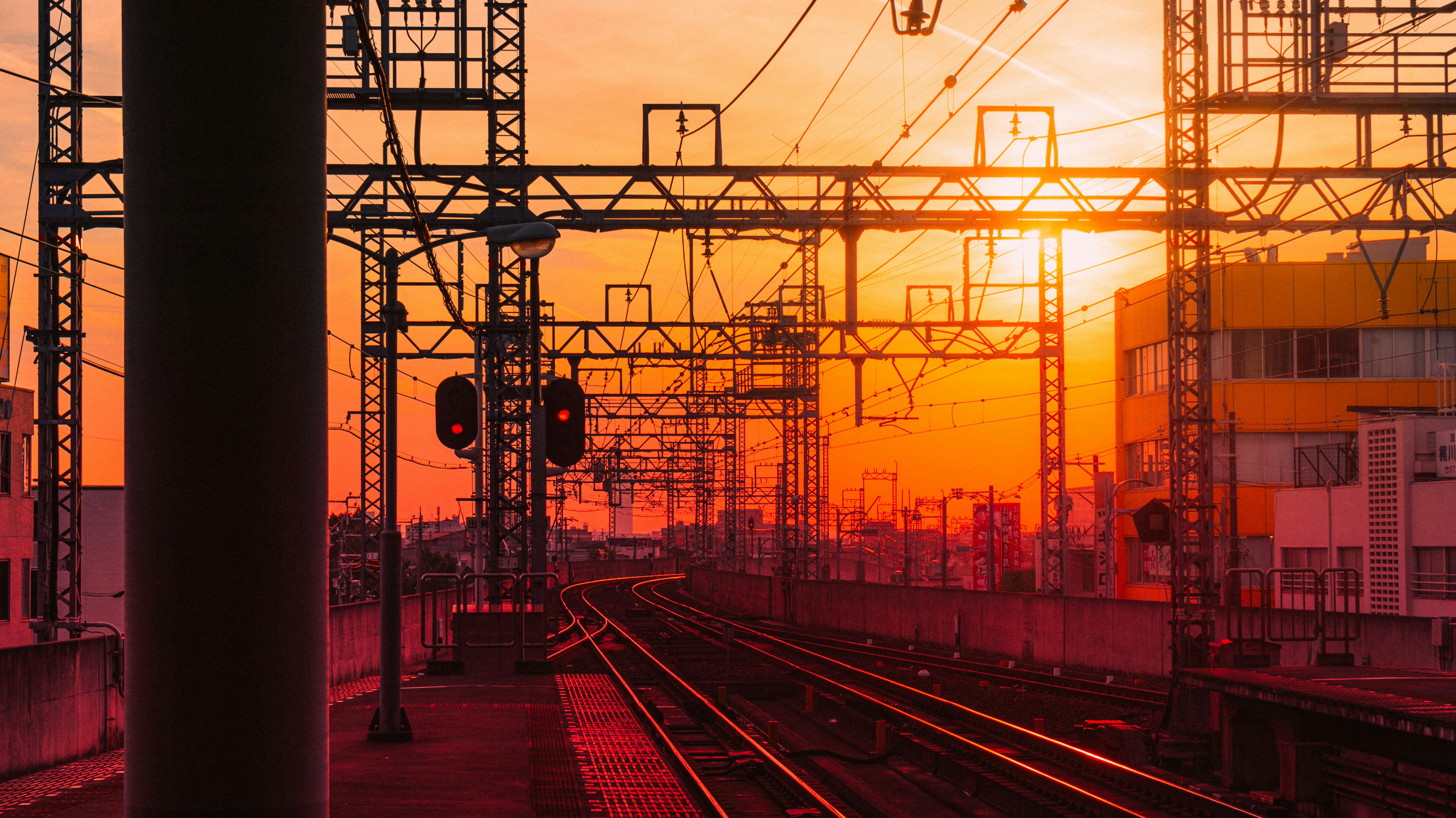 train rail near red and yellow building during sunset