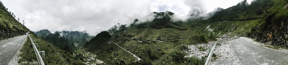 green grass field near mountain under white clouds during daytime