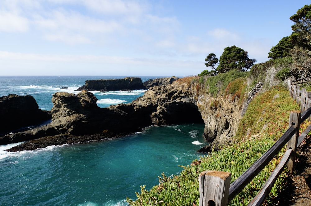 green and brown rock formation on blue sea under blue sky during daytime