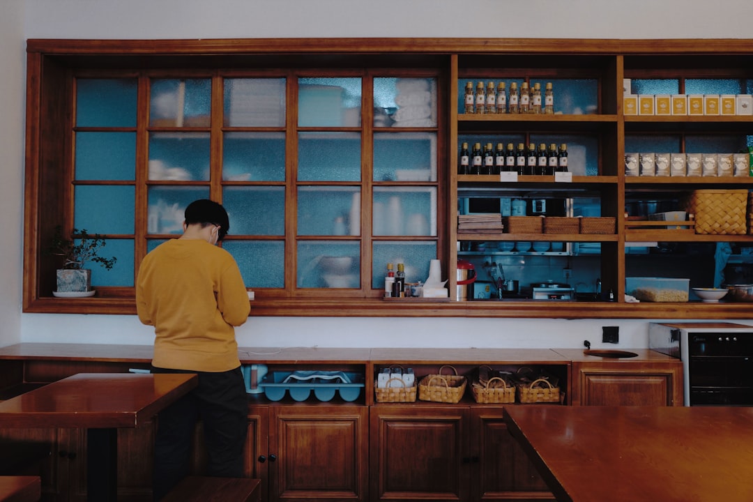 man in yellow shirt standing in front of brown wooden cabinet