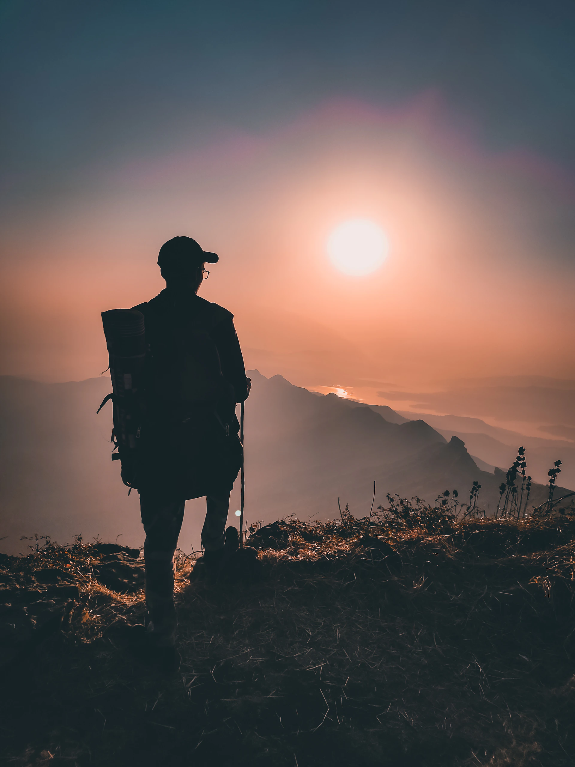 silhouette of man standing on grass field during sunset