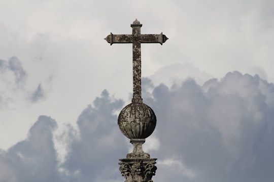 gold cross statue under white clouds during daytime in Braga Portugal