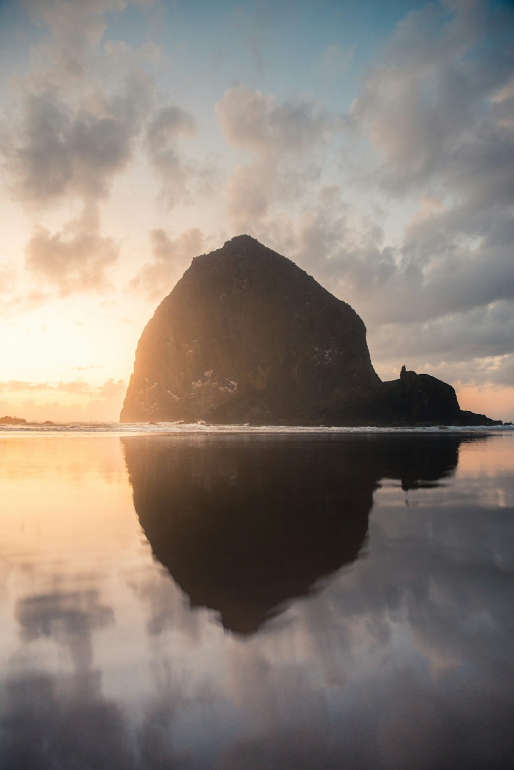 silhouette of mountain near body of water during sunset