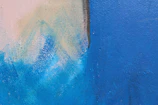 Close-up of decorative paint textures blending blue and gold hues in an artistic pattern.