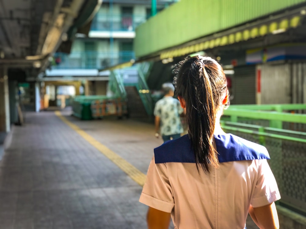 woman in brown t-shirt standing on sidewalk during daytime