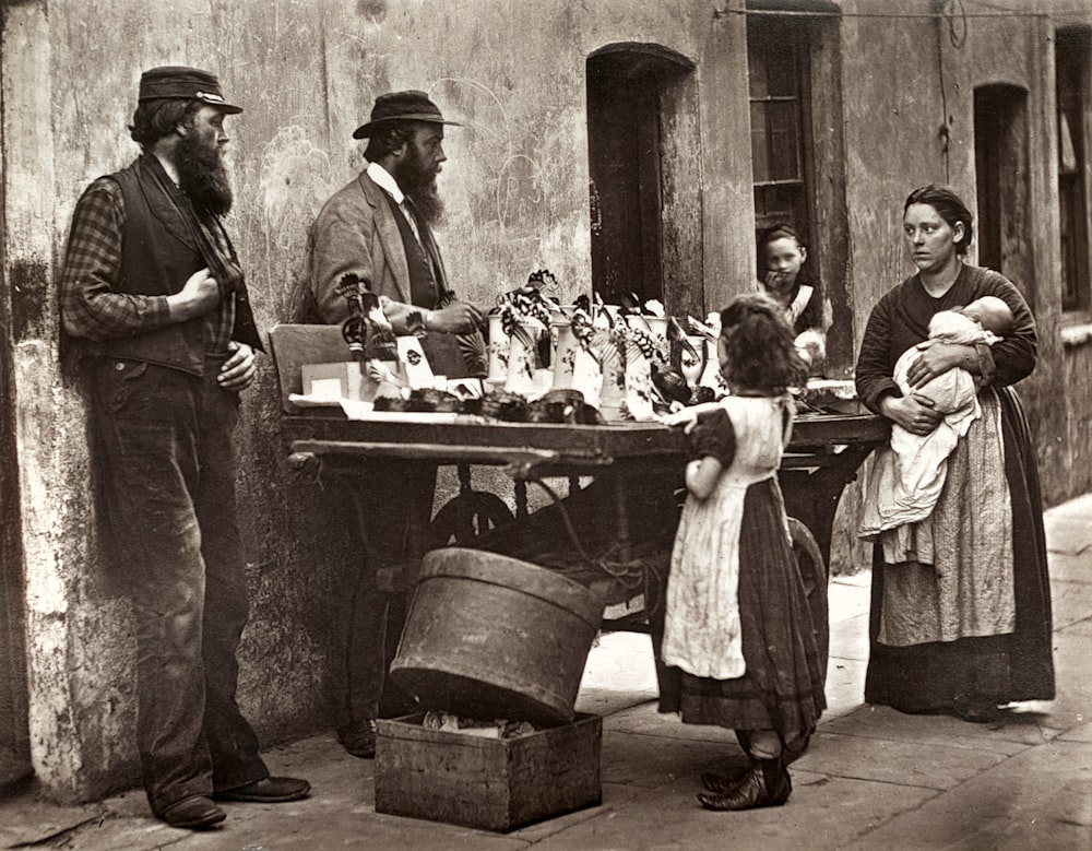 grayscale photo of people standing near table