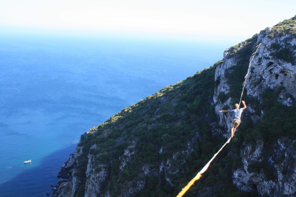 person in yellow shirt standing on cliff during daytime