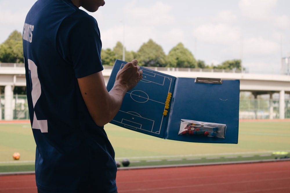 Mann im blauen T-Shirt mit Rundhalsausschnitt steht tagsüber auf dem Leichtathletikfeld