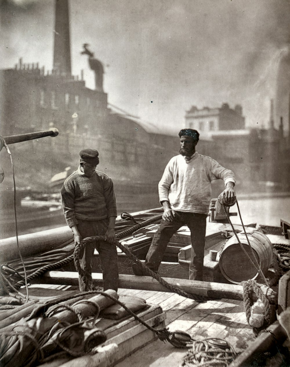 man in gray long sleeve shirt and black pants standing on brown wooden boat