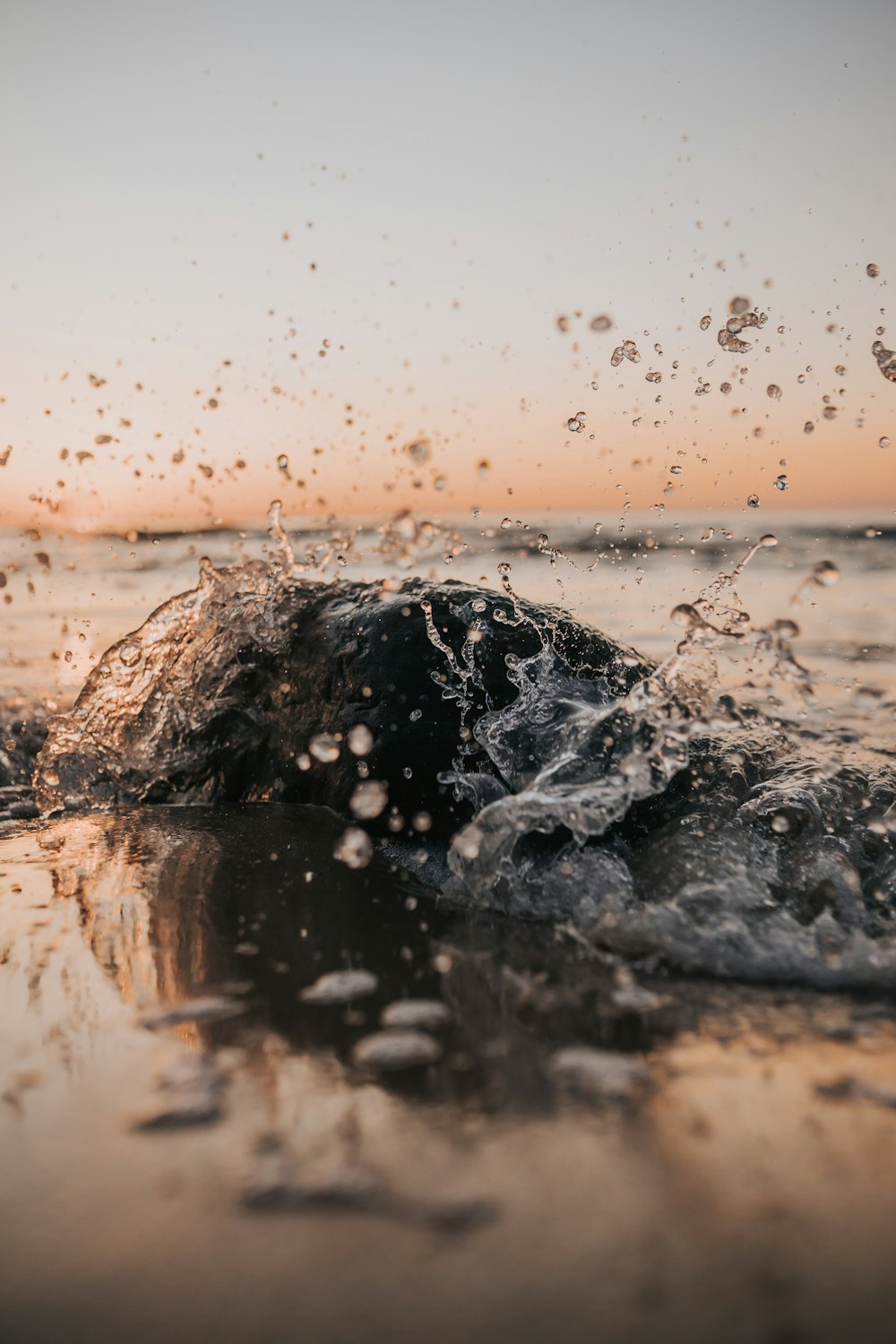 water splash on brown sand during daytime