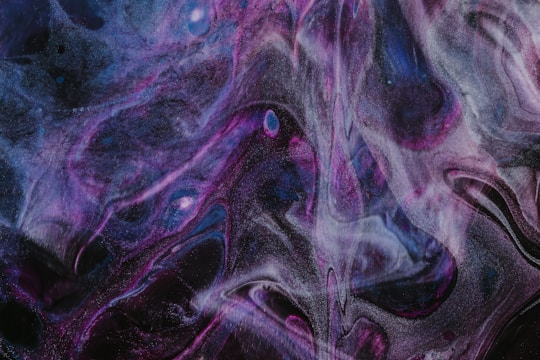 Swirling patterns of dark purple, black, and blue create a cosmic and abstract visual. Wisps of light and shadow weave together, evoking a sense of depth and mystery.