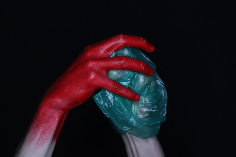 person holding red plastic bag