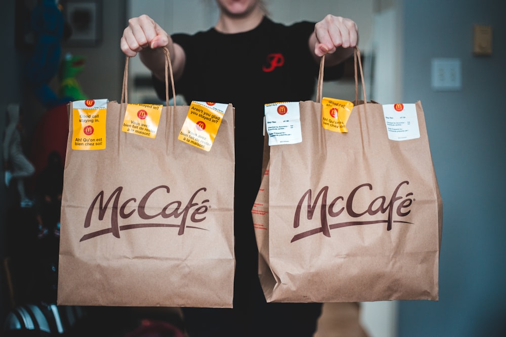 person holding white and brown tote bags