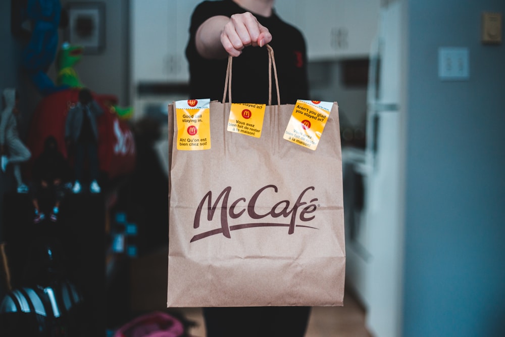 person holding white and brown paper bag