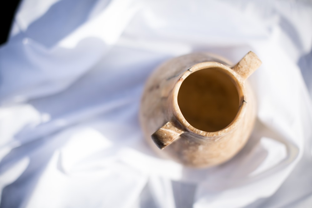 white ceramic mug on white textile