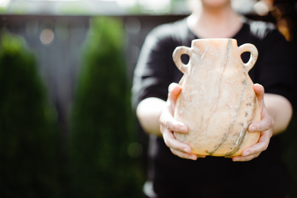 person holding brown ceramic pot