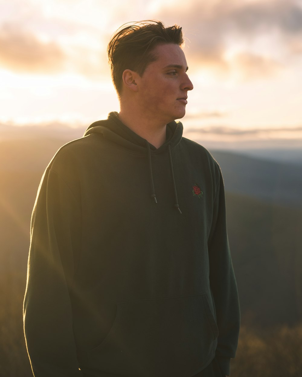 man in black hoodie standing on hill during daytime