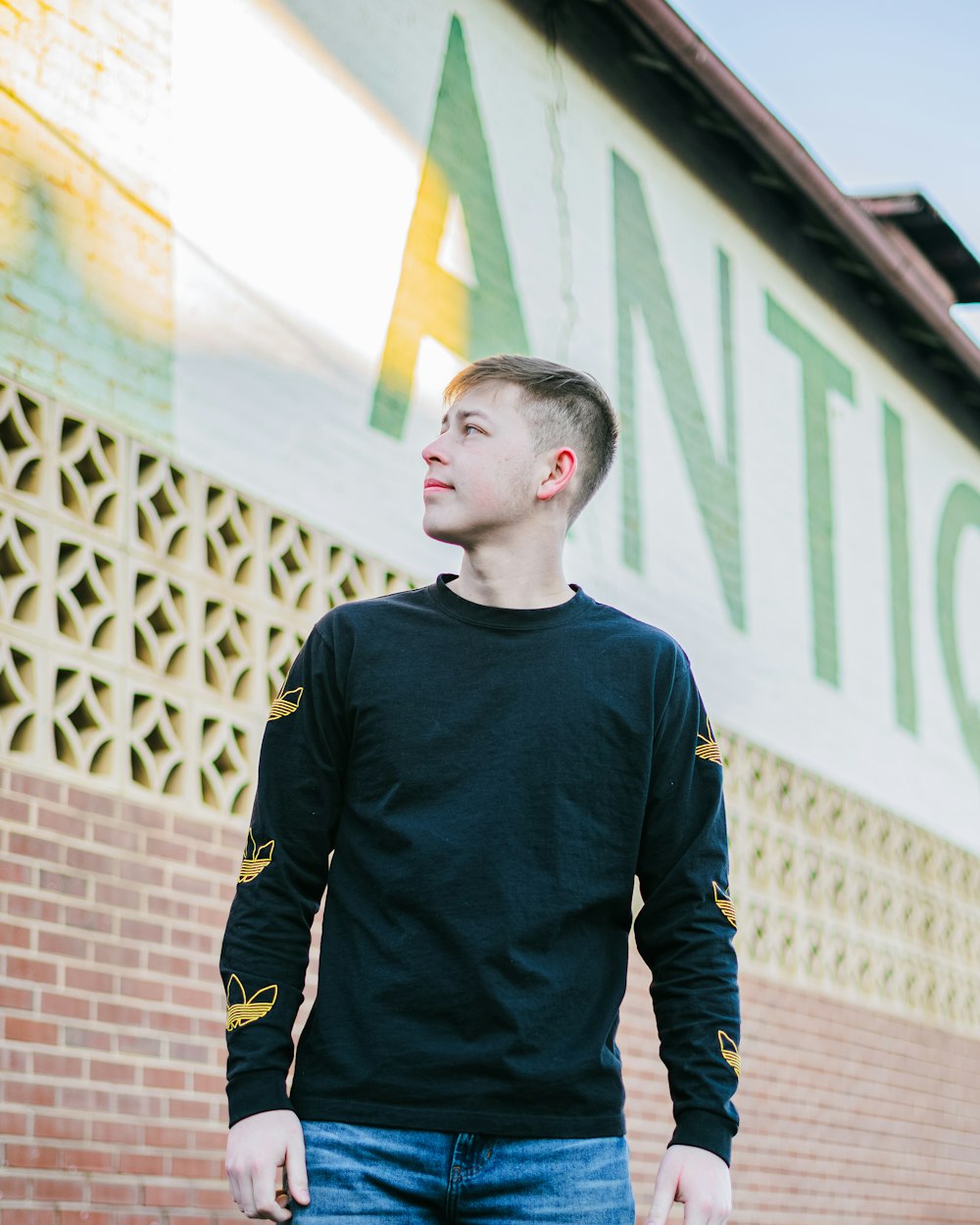 man in black and yellow long sleeve shirt standing on brown brick floor during daytime