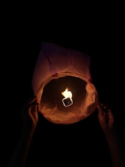 Hands crafting delicate paper lanterns with soft glowing light.