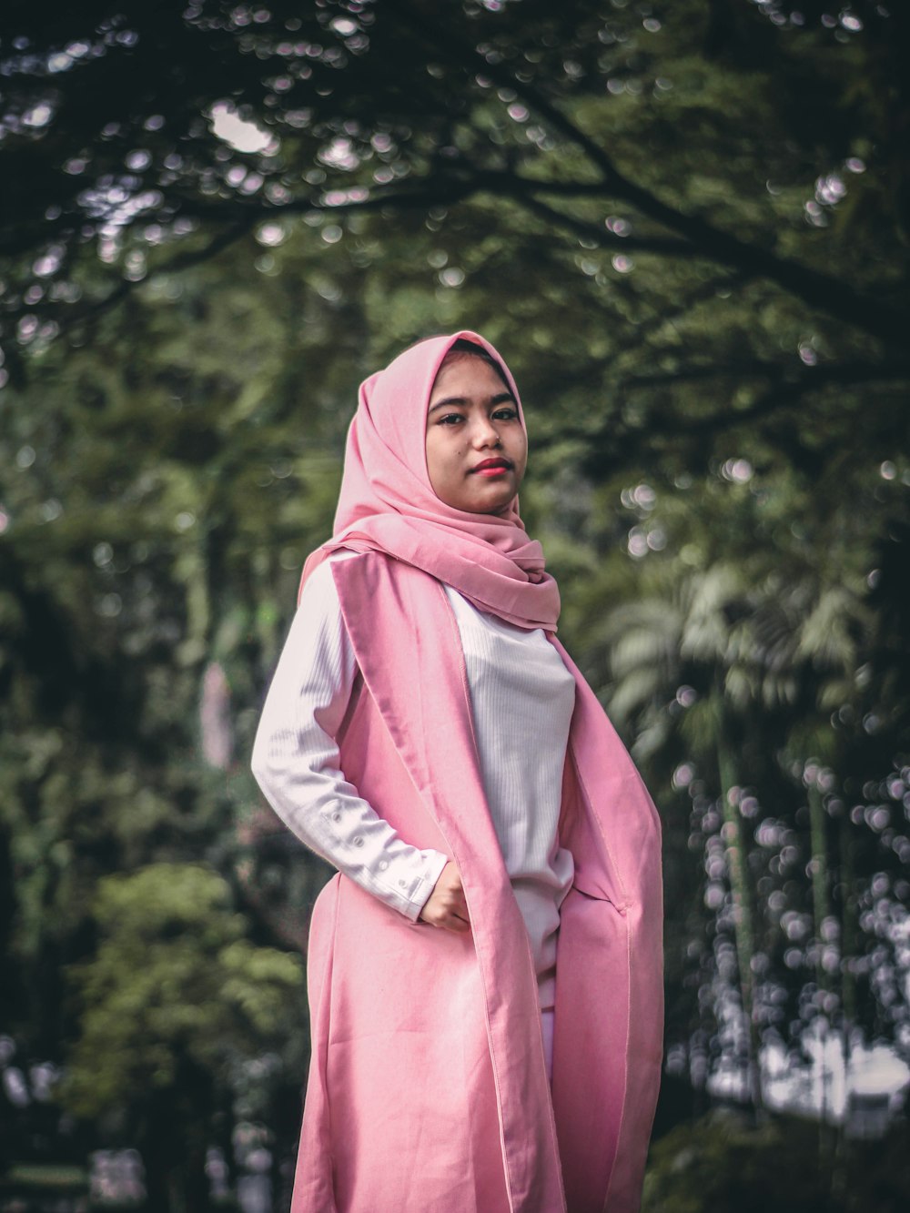 woman in pink hijab standing near green trees during daytime