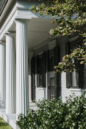 Front view of a charming portico with wooden columns and a shingled roof.