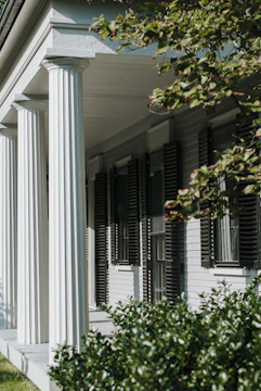 Front view of a charming portico with wooden columns and a shingled roof.