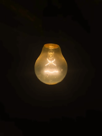 clear light bulb turned on in dark room