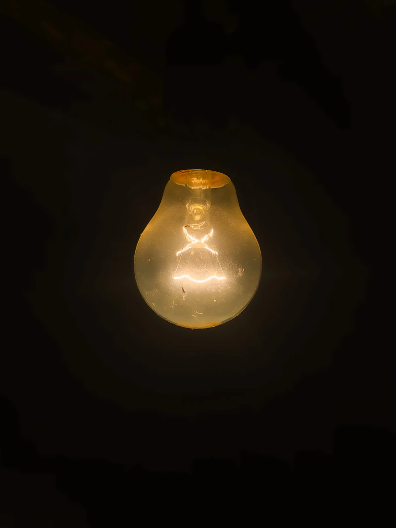 Fotografie: un bec transparent aprins într-o cameră întunecată