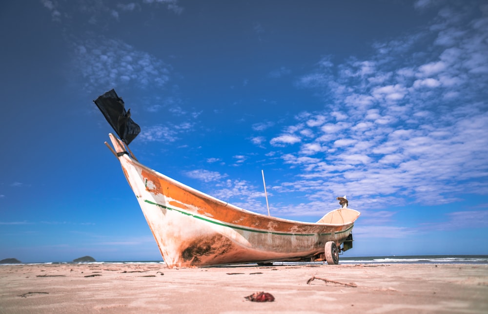 brown and white boat on brown sand under blue sky during daytime