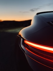 A sleek car being carefully loaded onto a modern transport truck at sunset.