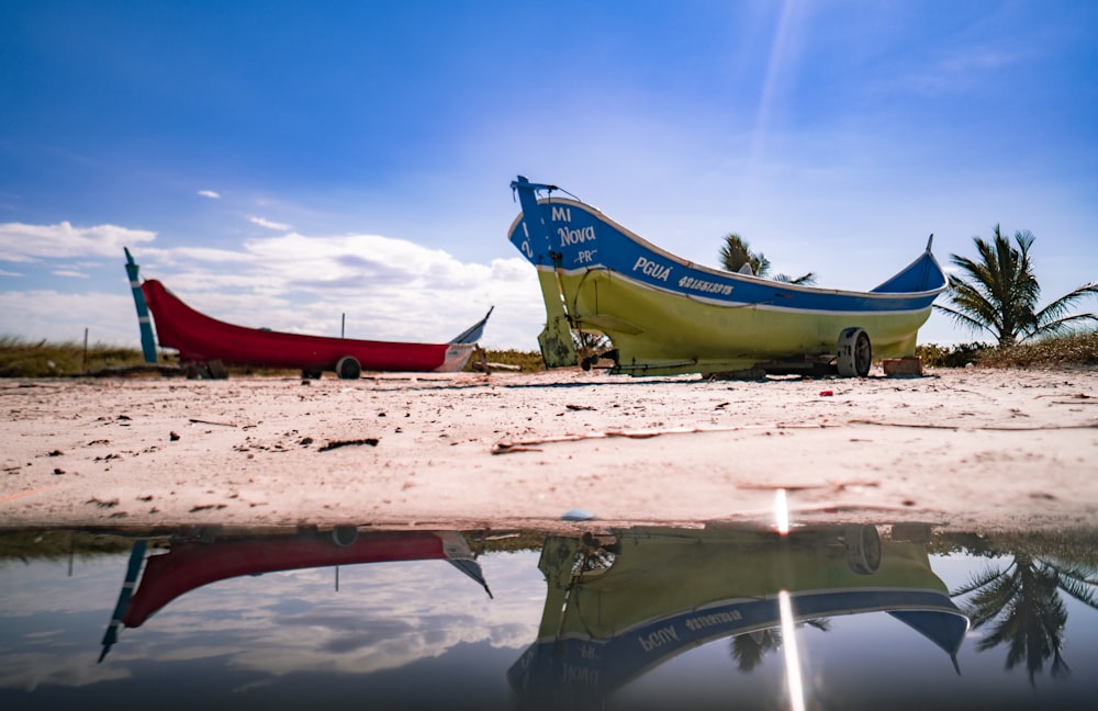 blue and red boat on brown sand during daytime