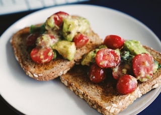 bread with tomato and green vegetable on white ceramic plate