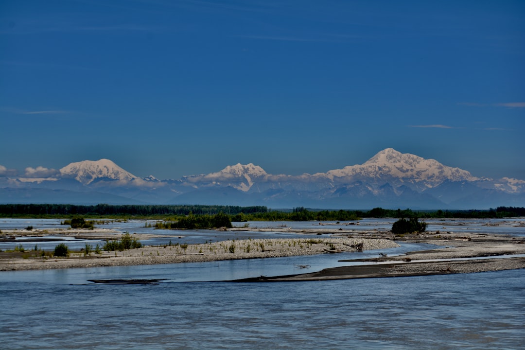 body of water near mountain under blue sky during daytime