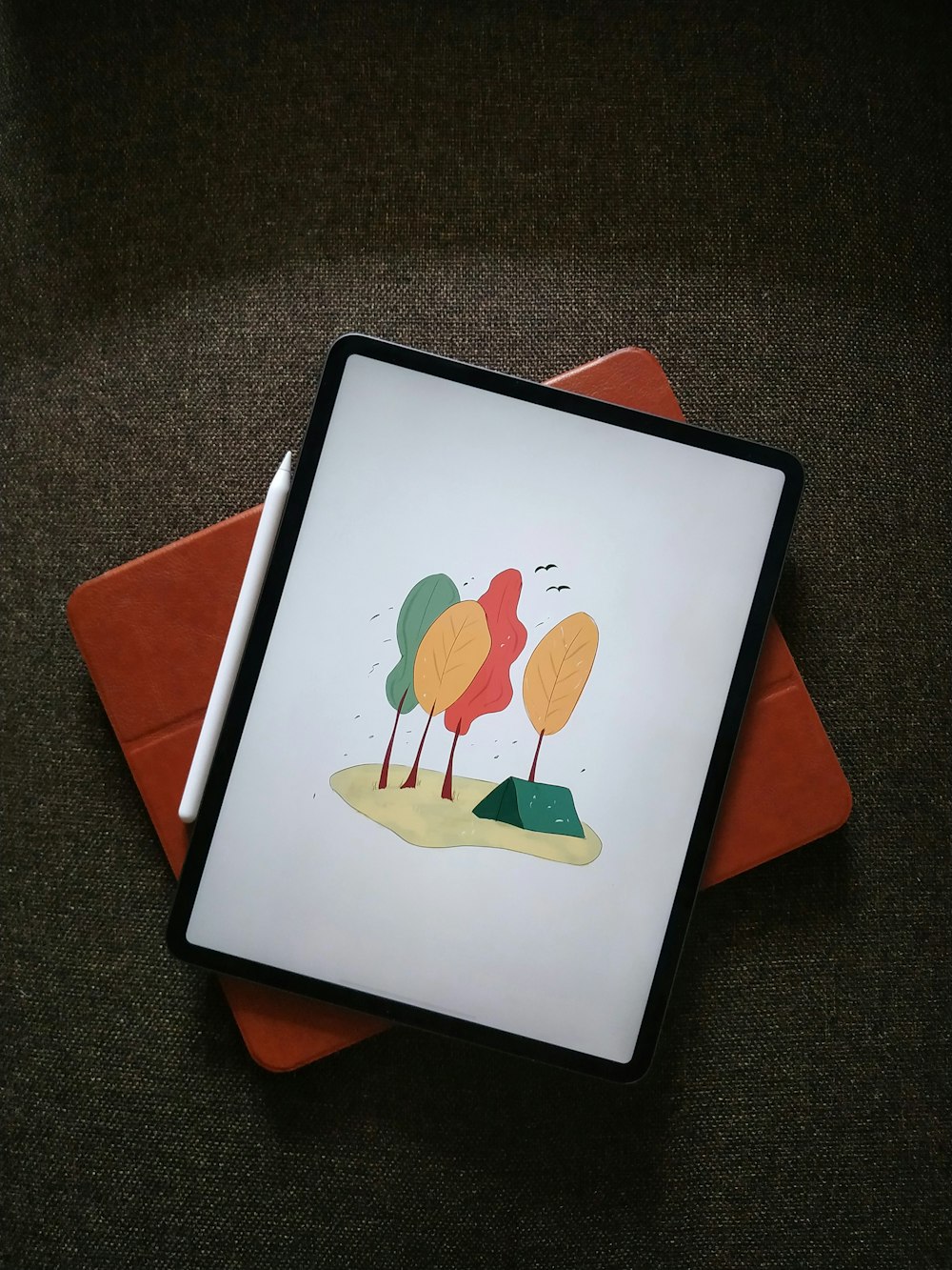 Weißes iPad auf orangefarbenem Textil