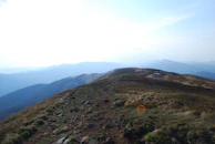A winding trail leading through rugged mountains under a clear sky.