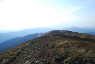 A winding trail leading through rugged mountains under a clear sky.
