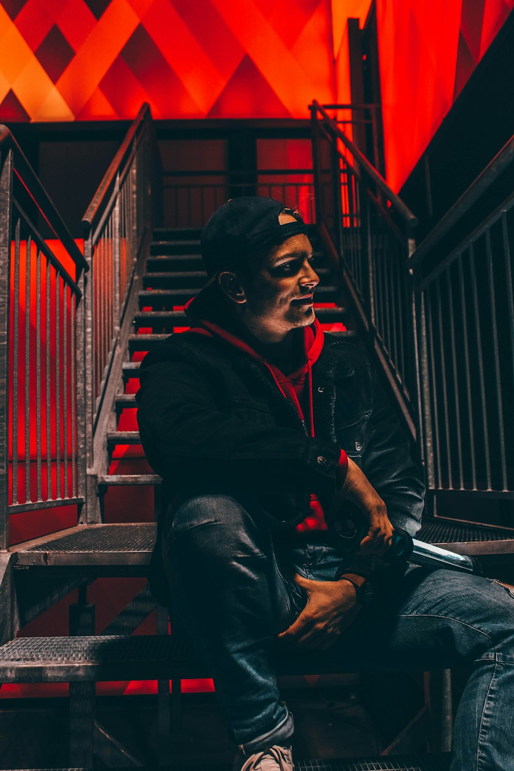 man in black jacket sitting on red bench