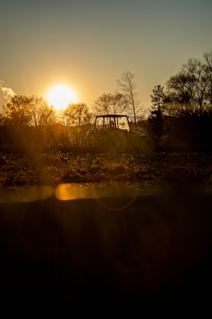 Sunset over endless rows of crops with a tractor parked nearby