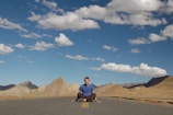 A person sitting cross-legged on a mountaintop, meditating under a clear blue sky.