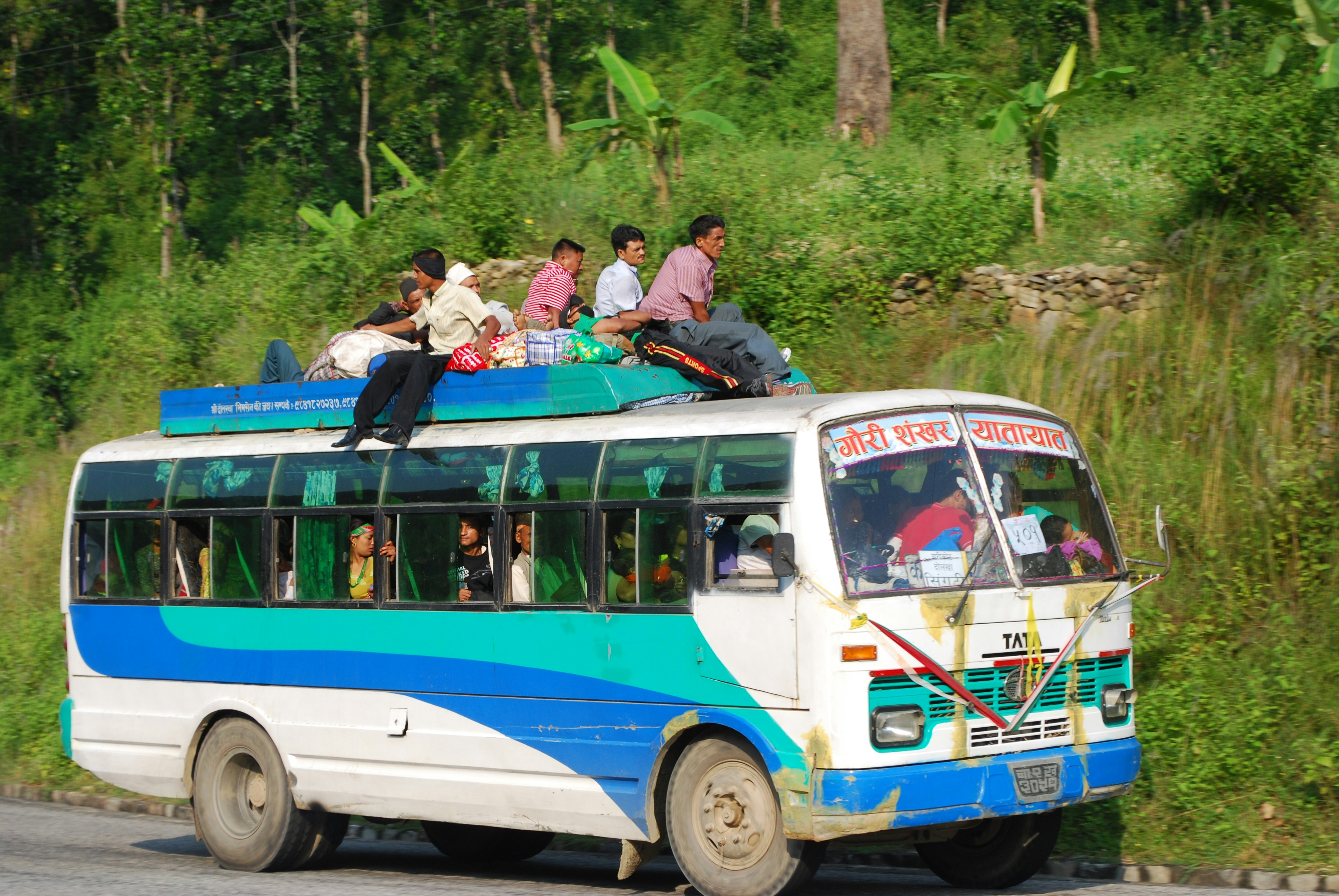 people riding blue and white bus during daytime
