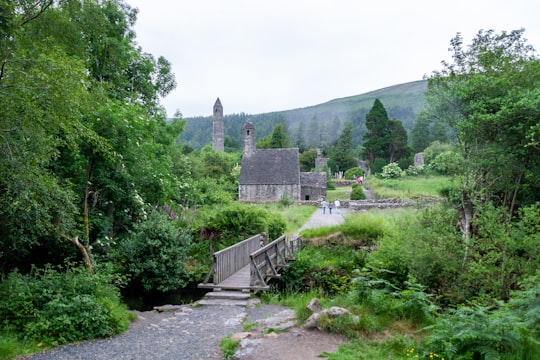 green grass field near gray concrete building during daytime in Glendalough Ireland