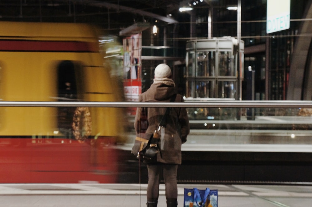 woman in brown coat standing near train