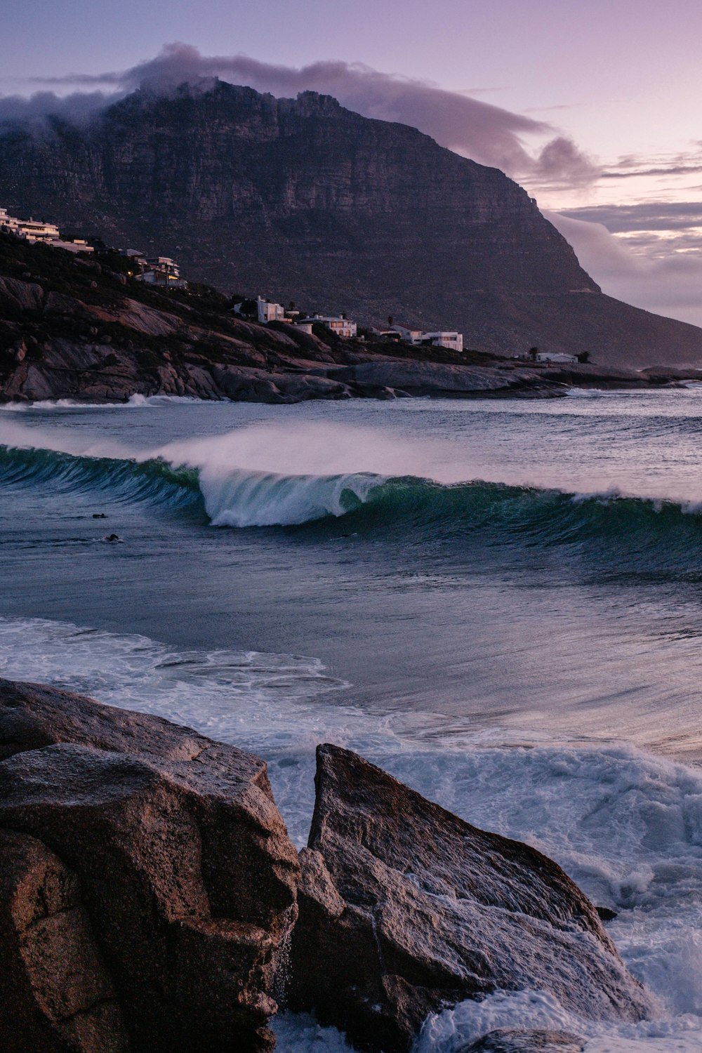 montanha rochosa marrom ao lado da água do mar durante o dia