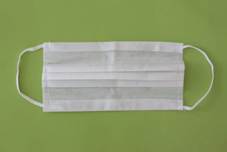 Disposable medical supplies like gloves and masks displayed on a light green background.